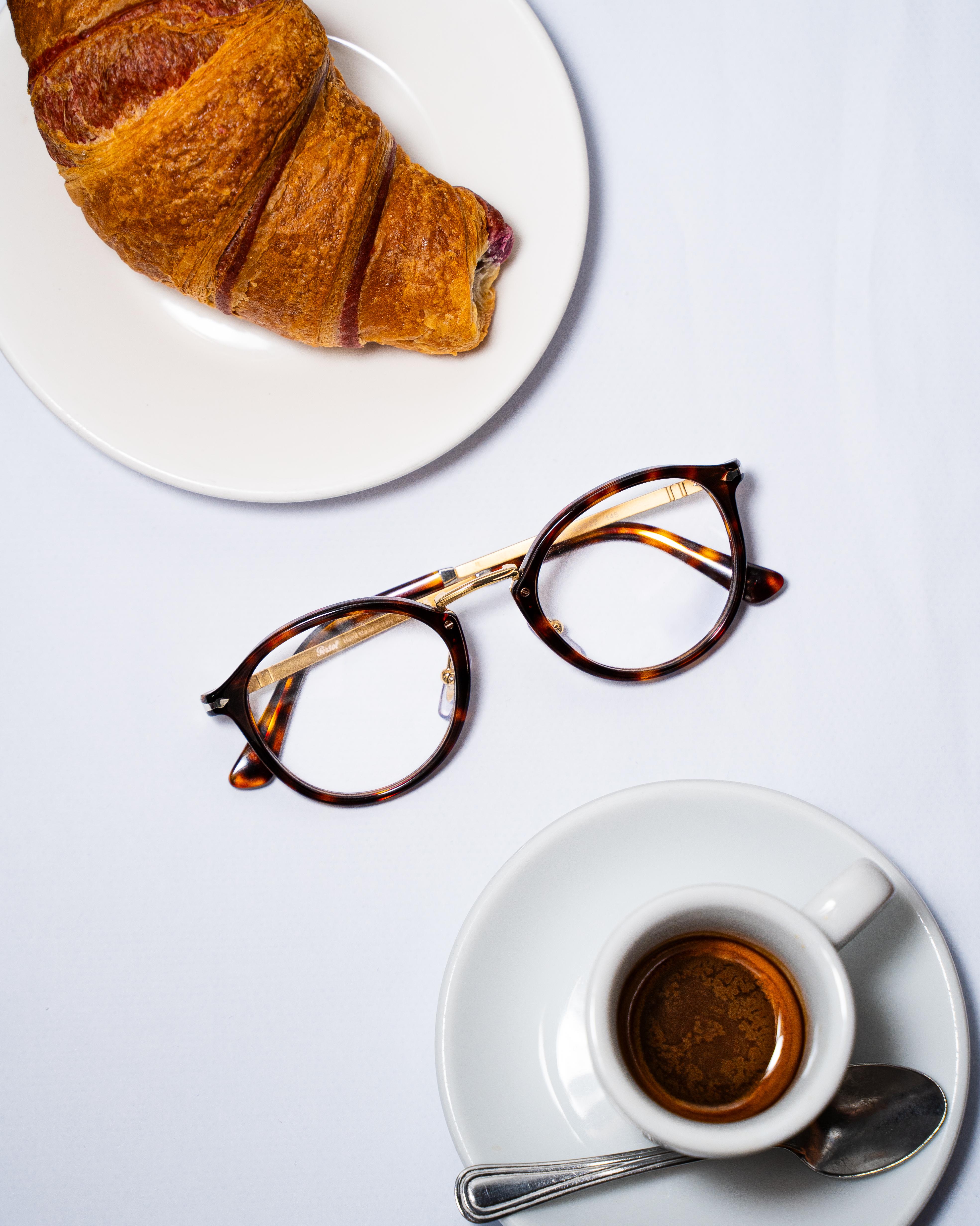 Occhiali da vista accanto a caffè e croissant